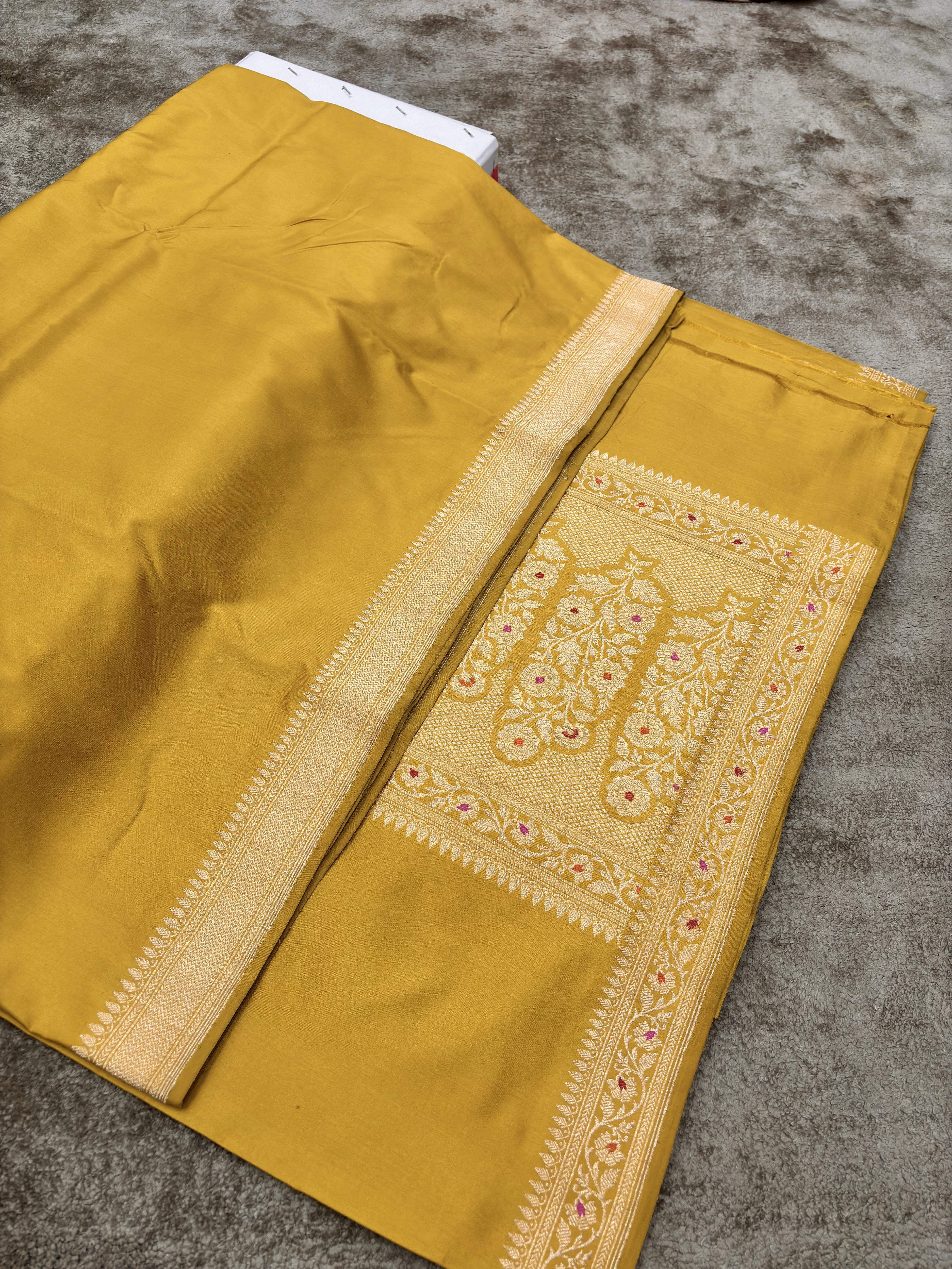 Handwoven yellow Pure Katan Silk Saree with a plain design and Minakari border pallu from Helm of Banarasi. BY HOB